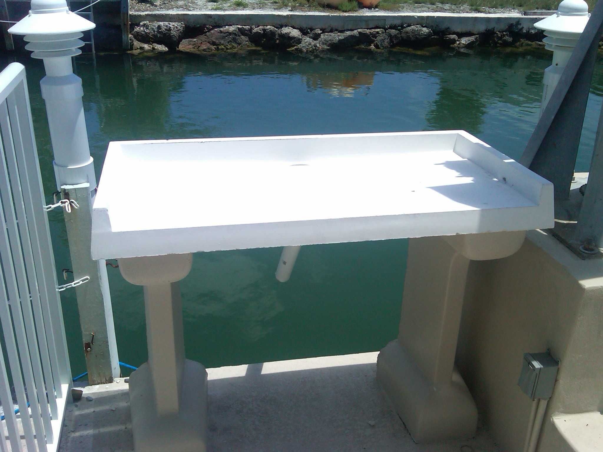A white outdoor sink attached to a balcony with a view of a calm body of water.