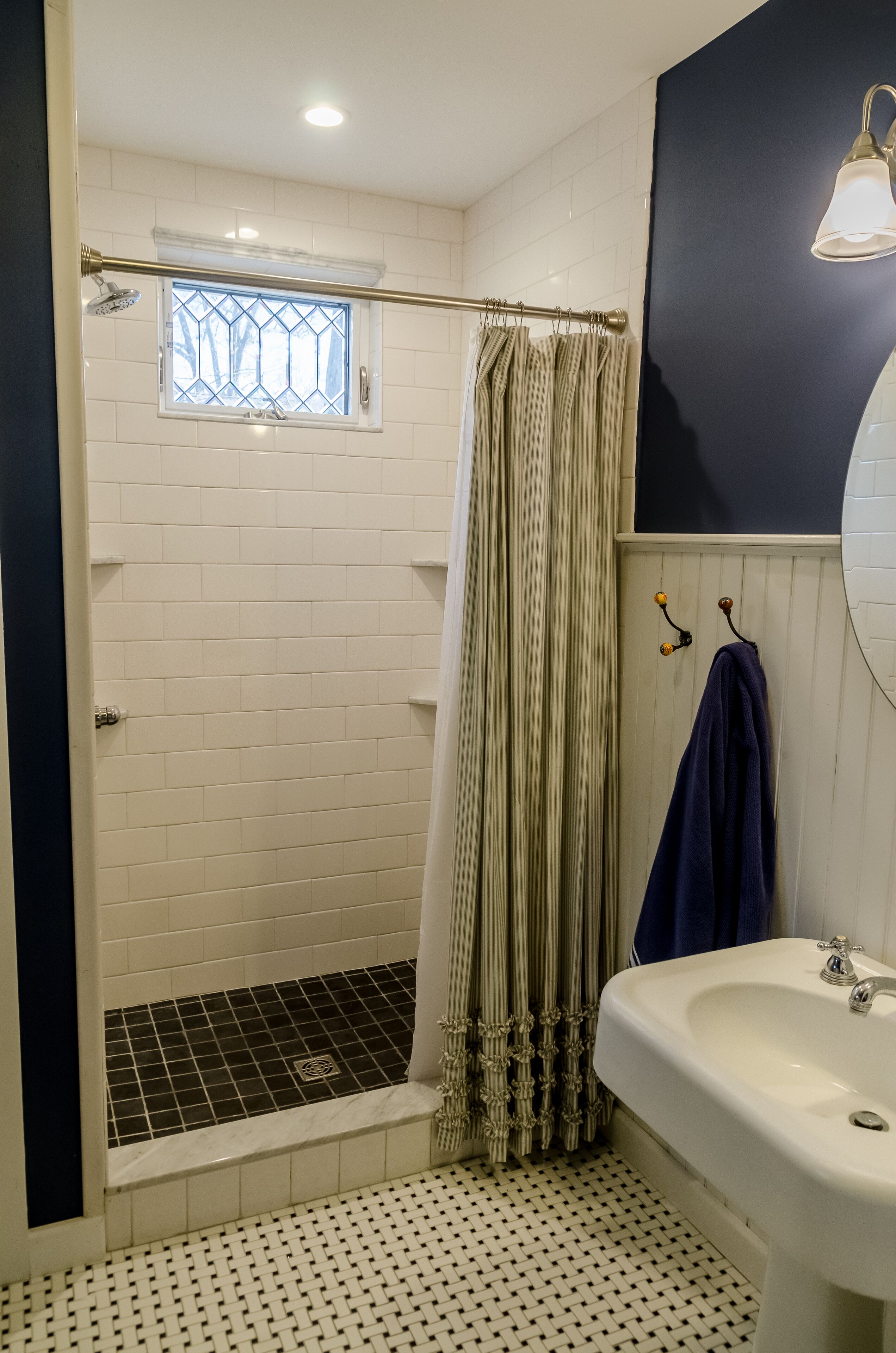 Un baño con ducha, lavamanos y una ventana con reja de metal.