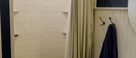 Un baño con ducha, lavamanos y una ventana con reja de metal.