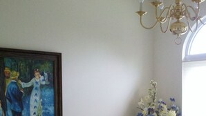Een eetkamer met een tafel voor vier personen, een bloevas en een schilderij aan de muur.