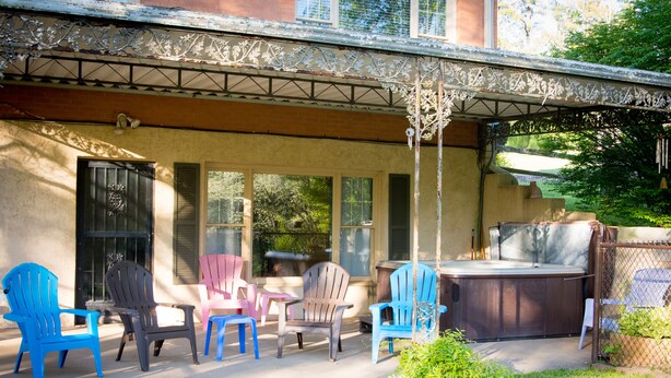 An outdoor patio with Adirondack chairs, a hot tub, and a covered area with a decorative metal railing. - Stay Where The Stars Stay! And we think everyone who stays with us is a STAR! (Nashville)