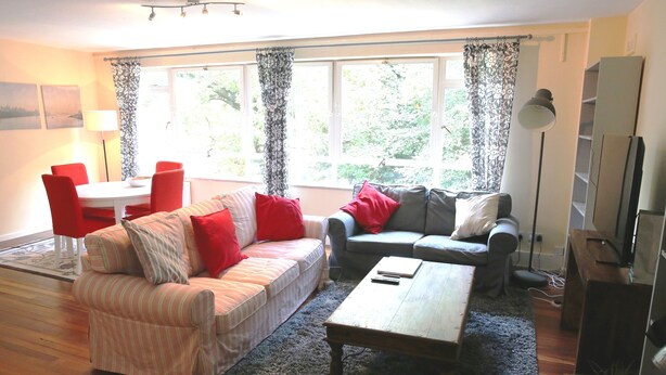 A living room with two sofas, a coffee table, a TV, and a dining area with a table and chairs. - Beautiful 2 Bedroom Private Apartment (London)
