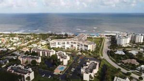 Luchtbeeld van een kusthotel met meerdere gebouwen, een parkeerplaats en uitzicht op de oceaan.