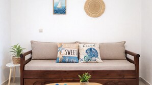 Ein gemütliches Wohnzimmer mit einer Holzdirektive, zwei Zierkissen, einem kleinen runden Tisch mit einer Pflanze und einem gerahmten Bild an der Wand.
