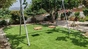 Relax in a serene garden setting with a charming wooden swing and lush greenery.