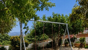 Ein Garten mit Schaukel, grünem Rasen und Topfpflanzen.