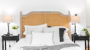 A neatly made bed with a woven headboard, two bedside tables with lamps, and a small potted plant on each table. - Quiet Glebe Studio Near Parks & Cafés (Glebe)
