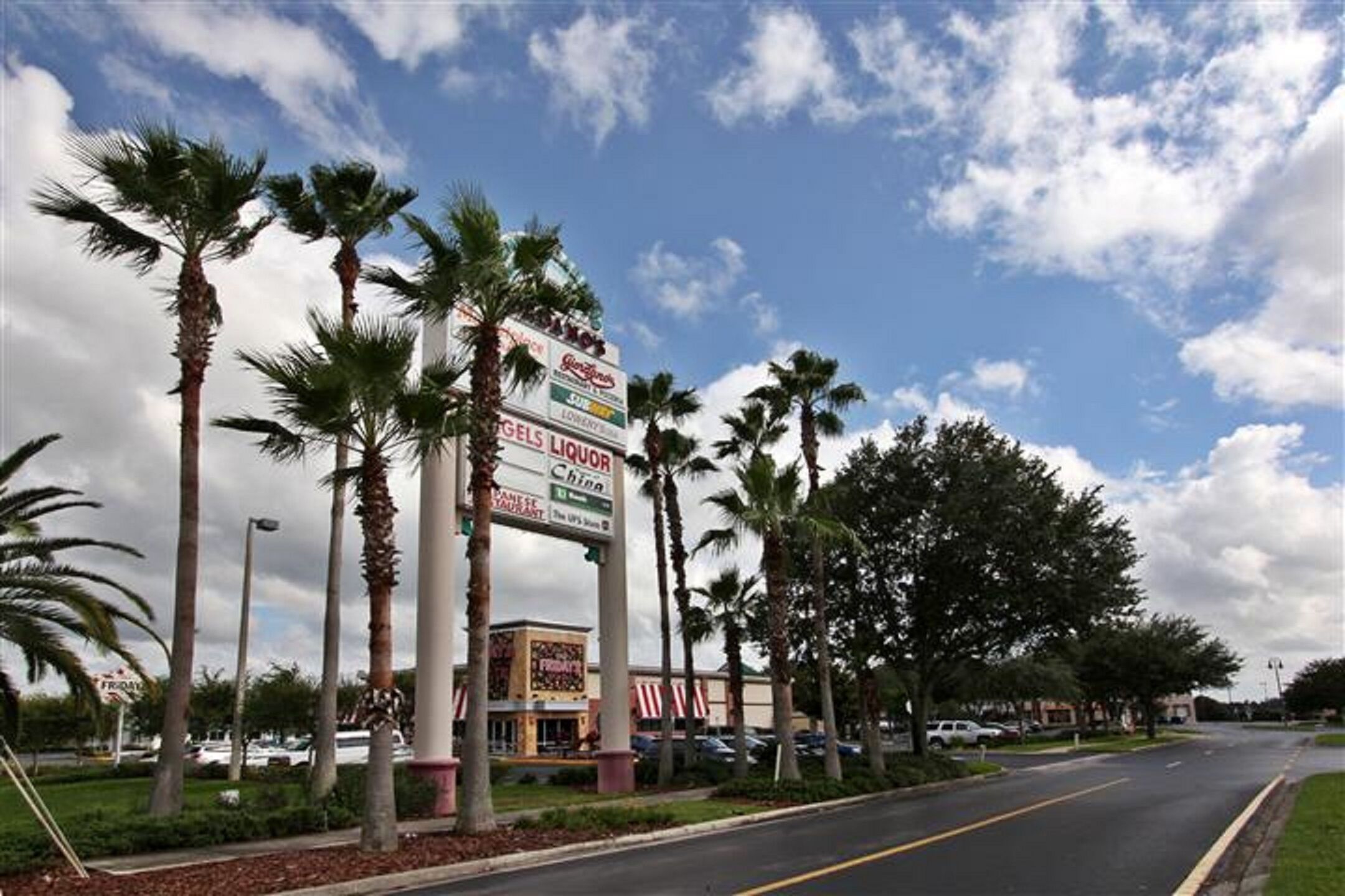 A commercial area with palm trees, a liquor store, and a restaurant.