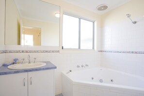 A bathroom with a white sink, a mirror, a window, and a bathtub. - Gannon (Lorne)