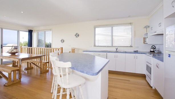 A modern kitchen with a central island, white cabinetry, and a view to the outside.