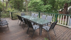 Une terrasse en bois avec une table à plateau de verre et six chaises.