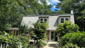 A two-story house with a wooden exterior, a front porch, and a pathway leading to the entrance.