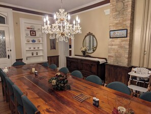 A dining room with a wooden table, chairs, a chandelier, a mirror, and a brick wall. - Historic registry farmhouse w/country feel, but close to Notre Dame! (Granger)