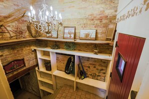 A cozy room with a brick wall, a chandelier, shelves with various items, and a red door. - Historic registry farmhouse w/country feel, but close to Notre Dame! (Granger)