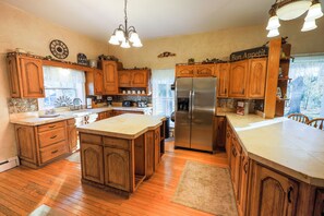 A spacious kitchen with wooden cabinets, a large island, and a stainless steel refrigerator. - Historic registry farmhouse w/country feel, but close to Notre Dame! (Granger)