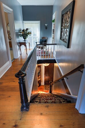 A staircase with a wooden handrail and a patterned carpet leading to a lower level. - Historic registry farmhouse w/country feel, but close to Notre Dame! (Granger)
