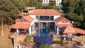 Ein großes Haus mit Swimmingpool, umgeben von Bäumen und anderen Gebäuden.