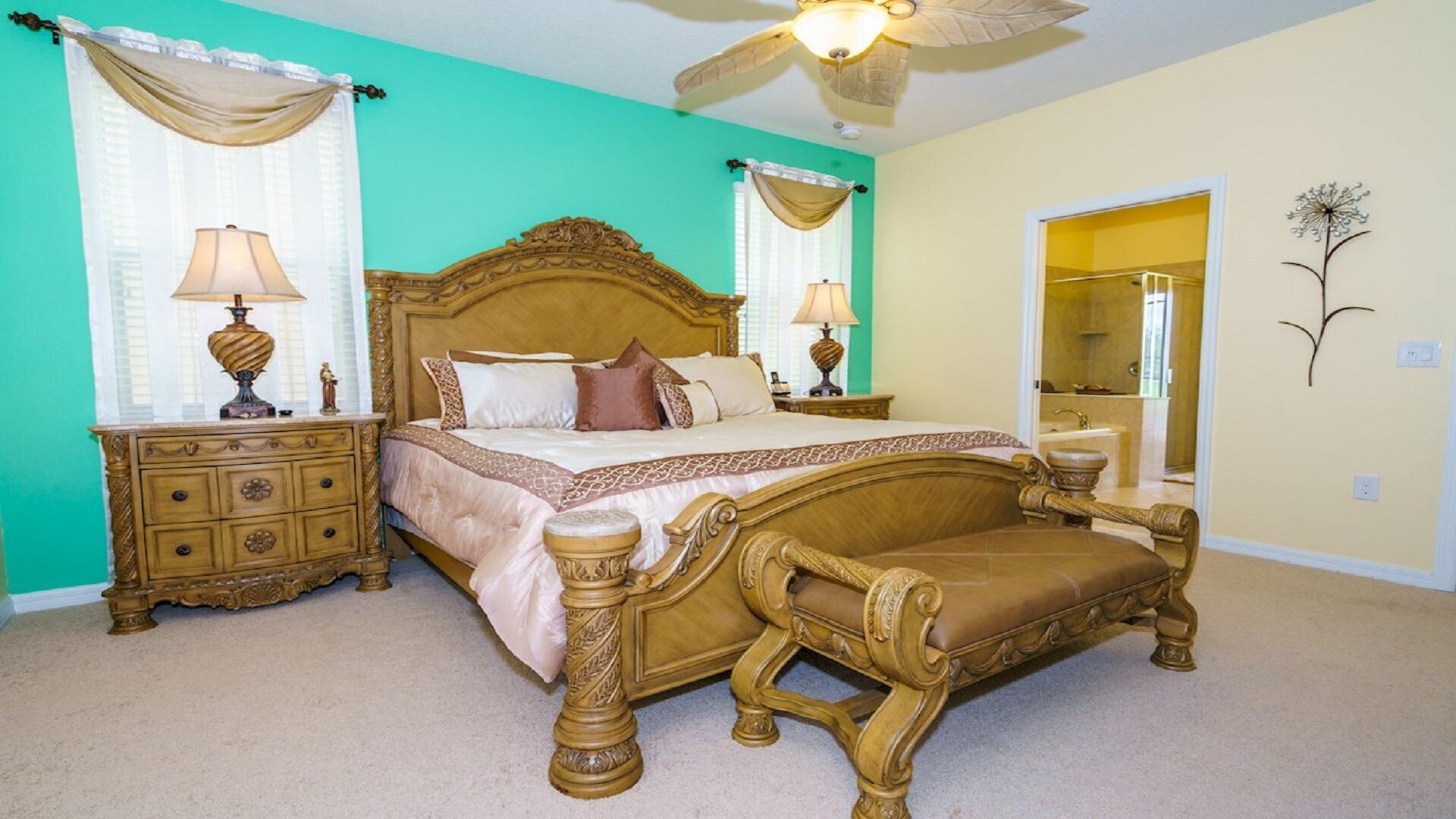 A bedroom with a large bed, two nightstands, a wooden bench, and a ceiling fan.