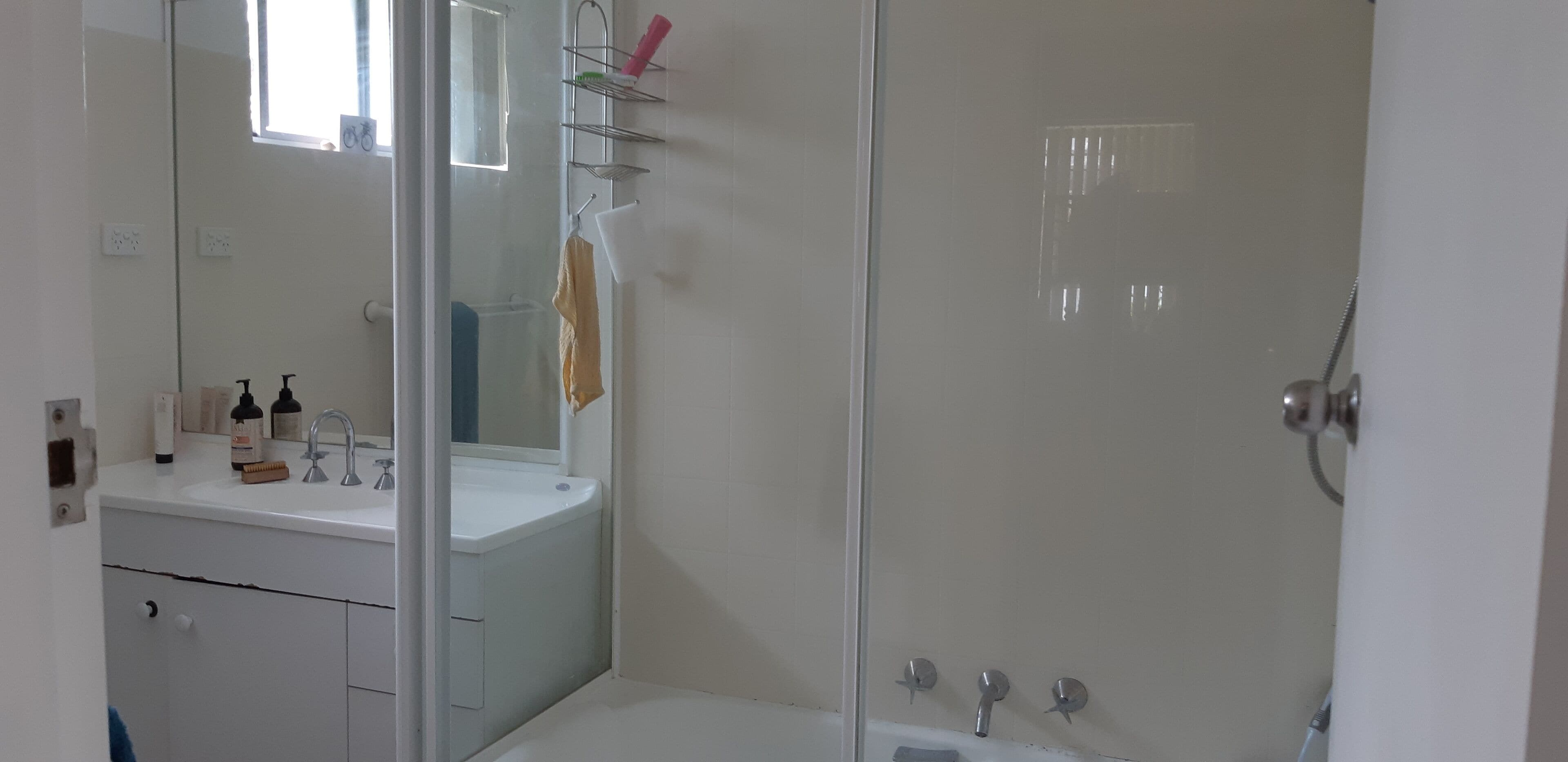 A bathroom with a white sink, mirror, and shower area.