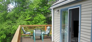 A balcony with a table and chairs, surrounded by lush greenery. - Spacious/Elegant 3 level house on Spruce Lake- swim or fish, short drive to Mt. (Wilmington)