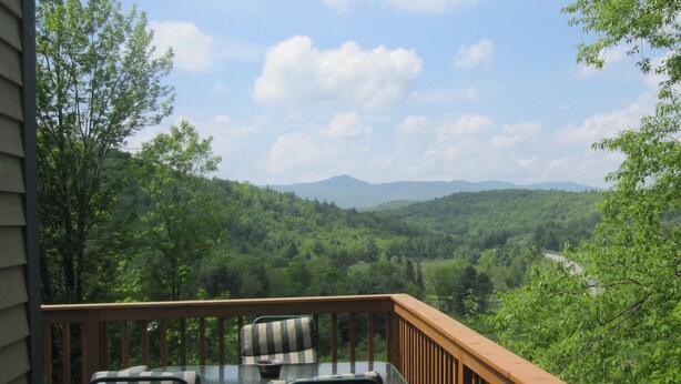 Une terrasse dotée de mobilier d’extérieur, offrant une vue sur un paysage montagneux.