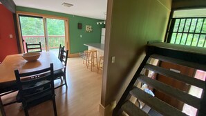 Un espace repas avec une table et des chaises, une cuisine à l’arrière-plan et un escalier menant à l’étage supérieur.