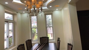A dining area with a long table, chairs, a chandelier, and large windows. - Beautiful two-level, fully furnished 4 bedroom house with WiFi (Kampala)