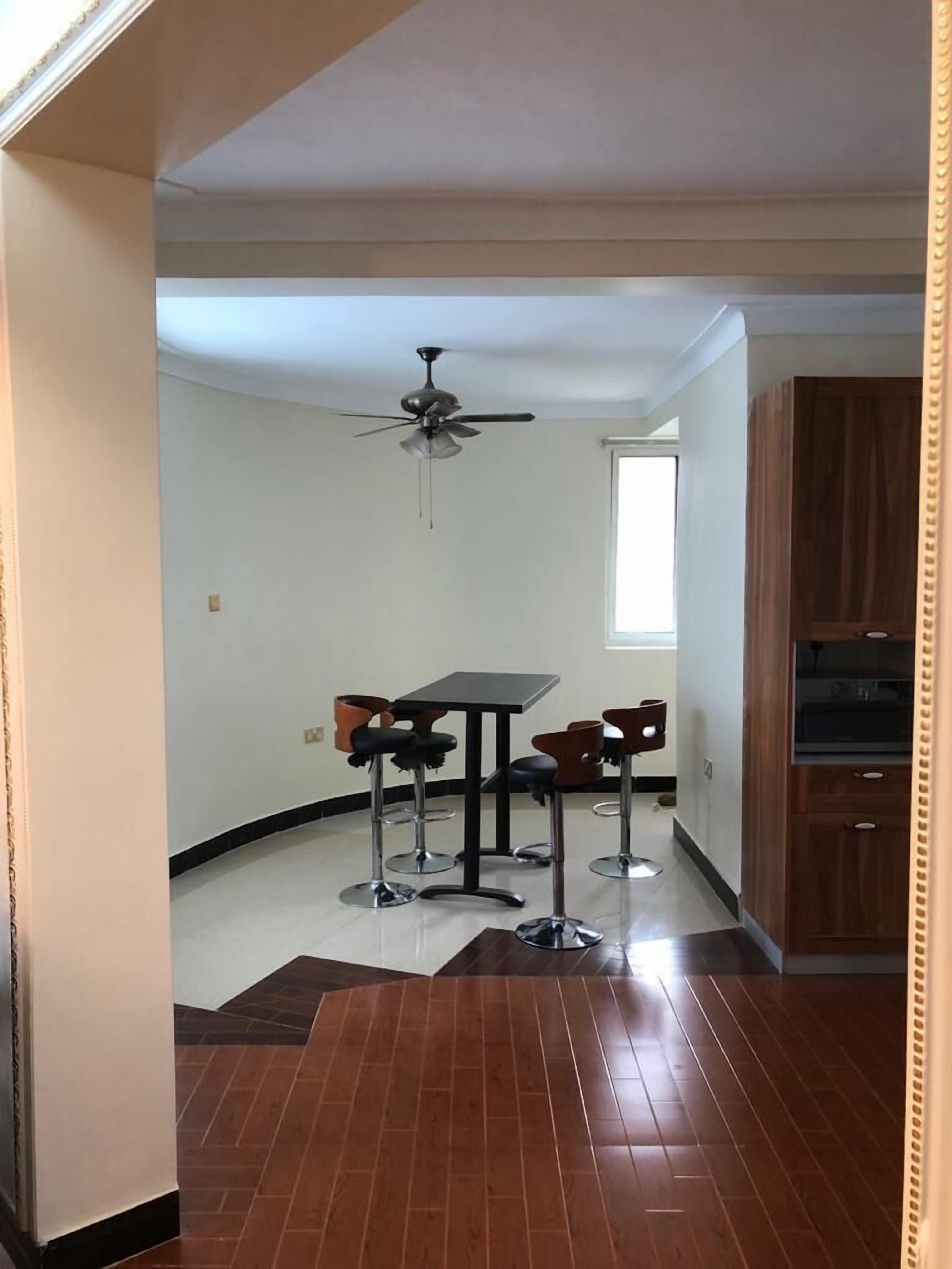 Une cuisine moderne avec un coin repas, un ventilateur de plafond et des armoires en bois.