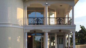 A two-story house with a balcony, a front porch, and a well-maintained lawn. - Beautiful two-level, fully furnished 4 bedroom house with WiFi (Kampala)