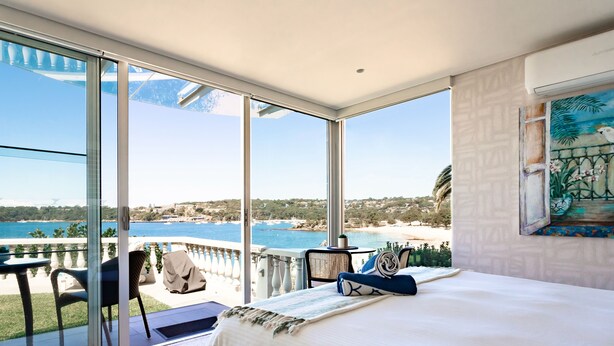 A bedroom with a large sliding glass door leading to a balcony with a view of the sea and a beach. - Balmoral Beauty - DIRECT BEACHFRONT - Romantic Studio Escape (Mosman)