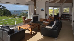A spacious living area with a fireplace, comfortable seating, and a view of the sea.