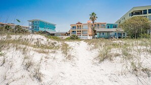 Il s'agit d'une propriété située en bord de mer, comprenant plusieurs bâtiments, dont un immeuble bleu remarquable et un immeuble beige doté de balcons.