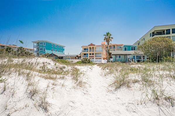 A beachfront property with multiple buildings, including a prominent blue building and a beige building with balconies. - Path to relaxation! (Indian Rocks Beach)