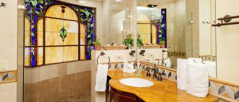 A bathroom with a glass shower enclosure, a marble sink, and a large mirror.