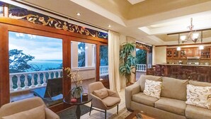 A spacious living area with a sofa, armchairs, a coffee table, and a view of the ocean.