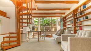 A cozy living room with a wooden staircase, a sofa, a coffee table, and a bookshelf. - Breathtaking Clifton 4th beach villa (Clifton)