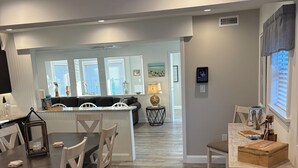 A modern kitchen with a dining area, featuring a central island, white cabinetry, and a view of the living room. - Beautiful & Newly Renovated, 6 Br, 4 Bath,Open floor plan  (Brigantine)