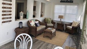 A cozy living room with wicker furniture, a glass table, and a sign reading "Seashells" on the wall. - Beautiful & Newly Renovated, 6 Br, 4 Bath,Open floor plan  (Brigantine)