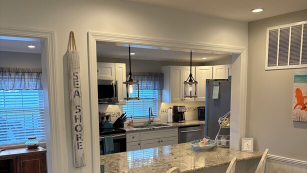 A modern kitchen with a granite countertop, white cabinetry, and pendant lighting. - Beautiful & Newly Renovated, 6 Br, 4 Bath,Open floor plan  (Brigantine)