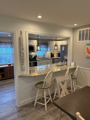 A modern kitchen with a granite countertop, white cabinetry, and pendant lighting. - Beautiful & Newly Renovated, 6 Br, 4 Bath,Open floor plan  (Brigantine)