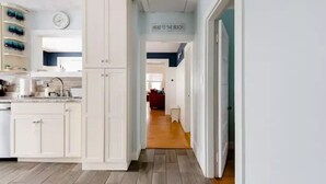 A kitchen with white cabinets, a clock, and a sign that says "Head to the beach." - Adorable Beach House Across the Street From Beach! (Scarborough)