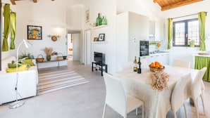 A modern kitchen with white cabinets, a dining area with a table set for two, and a living room with a sofa and a TV. - Trappeto Dellago with pool, parking & wi.fi  (Avola-Noto (siracusa))