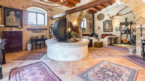 A rustic room with stone walls, wooden beams, a large stone mill, and traditional rugs. - Trappeto Dellago with pool, parking & wi.fi  (Avola-Noto (siracusa))