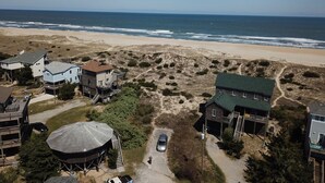 Vista aérea de una zona residencial costera con casas, una playa y dunas.