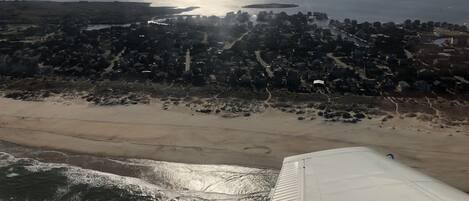 An aerial view of a coastal area with a beach, a small island, and a densely populated town.