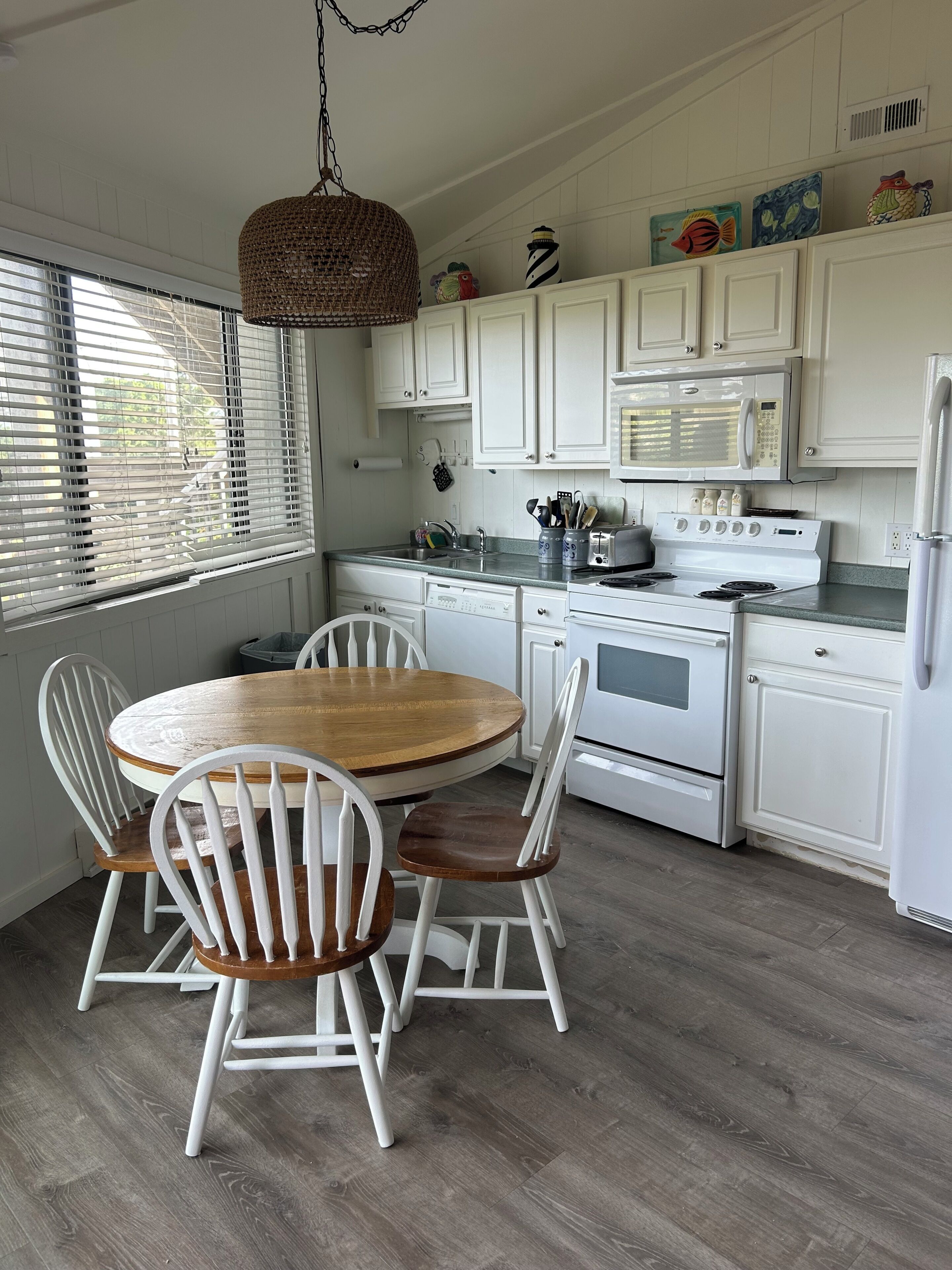 Una cocina con armarios blancos, una mesa de madera y sillas.