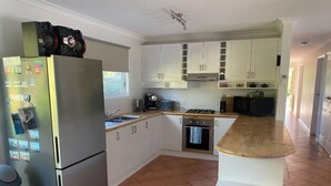 A kitchen with white cabinets, a stainless steel refrigerator, a wooden countertop, and a tiled floor.