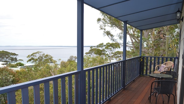 A wooden deck with a blue railing, overlooking a body of water and trees.