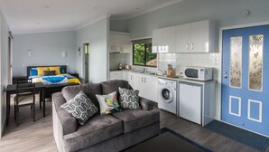A compact living space with a kitchenette, a dining area, and a sofa with patterned cushions.
