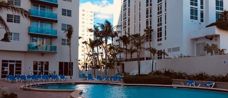 A pool area with lounge chairs and palm trees.